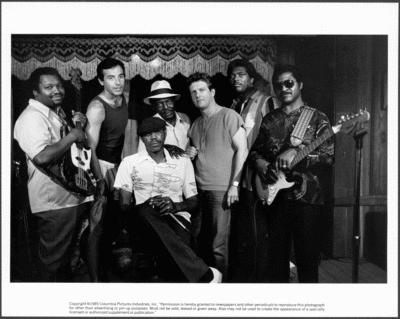 8 inch x 10 inch black and white photograph.  Photograph by Stephen Vaughan.  Some of the musicians featured in the Crossroads soundtrack (L-R):  Richard 'Shubby' Holmes, Ry Cooder, Frank Frost (seated), John Price, John 'Juke' Logan, Terry Evans, and Otis Taylor. 